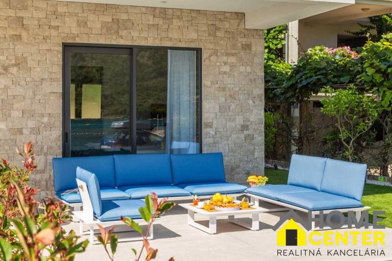 Exteriér vily v Bale s modrým zahradním posezením a kamennou zdí.