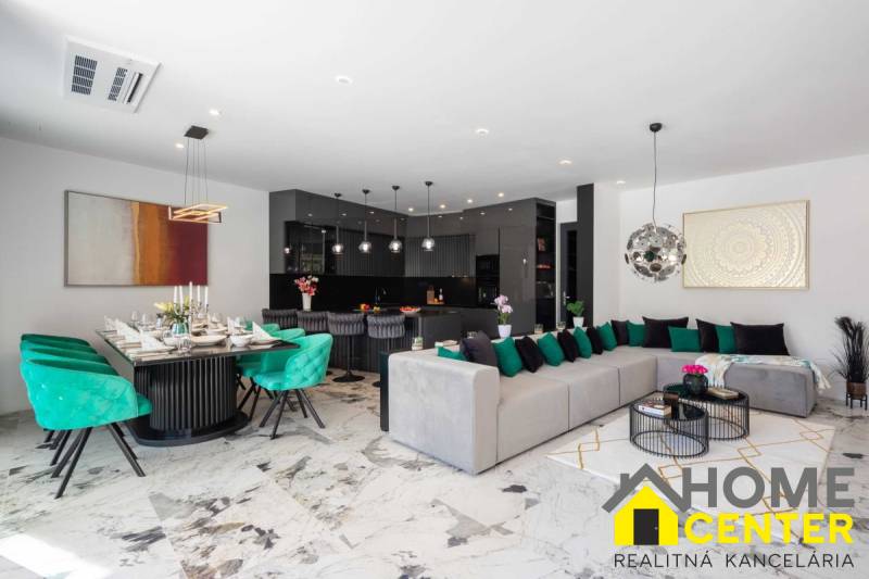 Prostorný obývací pokoj vily s jídelnou, sedačkou a moderní kuchyní.