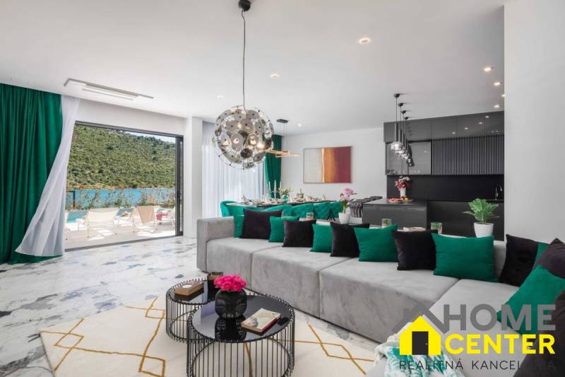 Prostorný obývací pokoj vily s výhledem na bazén a přírodní prostředí.