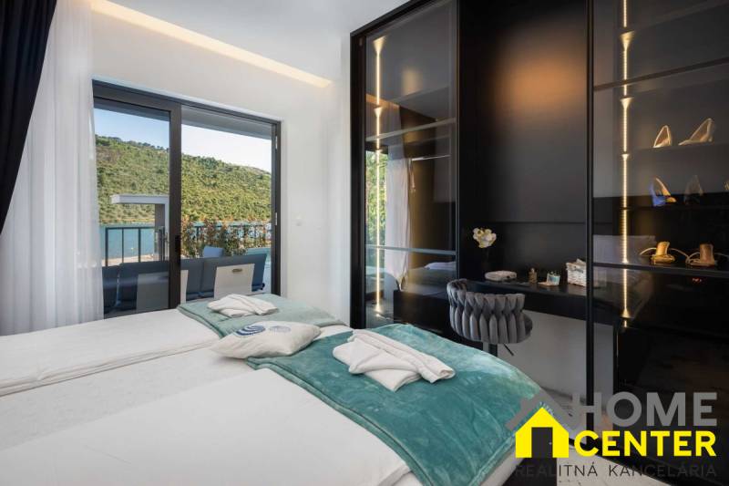 Ložnice ve vile s terasou a výhledem na přírodu a jezero.