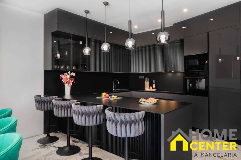Černá kuchyně ve vile s mramorovou podlahou a luxusními židlemi.
