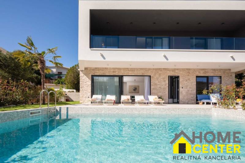 Vila v Bale s bazénem, palmami, terasou a lehátky na pozadí.