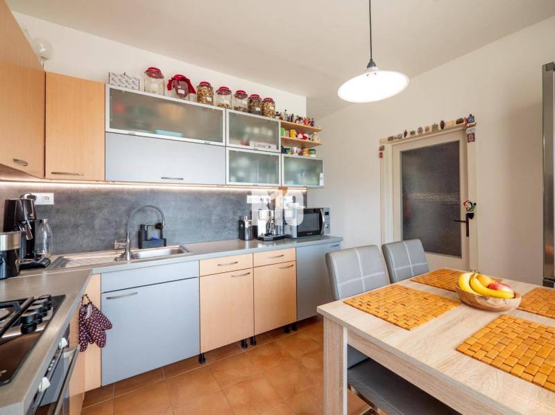 Kuchyně ve 4-pokojovém bytě s počítačem a kuchyňskou linkou v dřevěném dekoru.