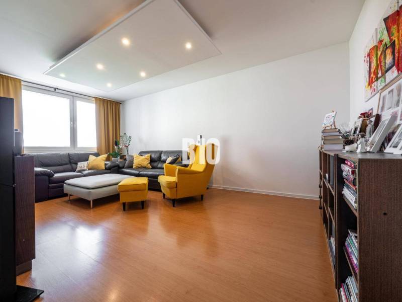 Obývací pokoj ve 4pokojovém bytě s podlahou s dřevěným dekorem a pohodlným nábytkem.