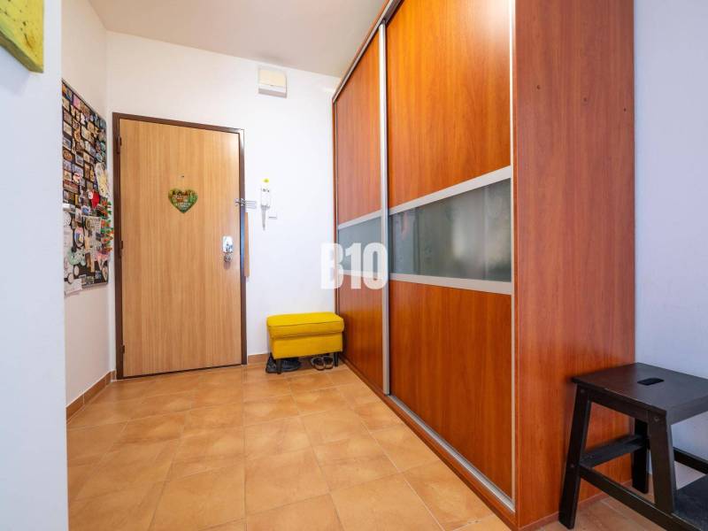 Chodba ve 4-pokojovém bytě s dlažbou a vestavěnou skříní.