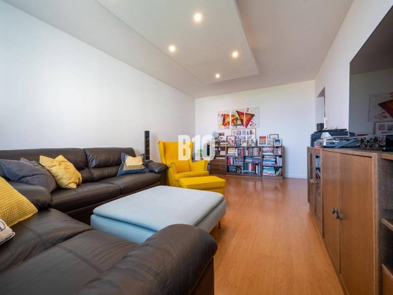 Obývací pokoj ve 4pokojovém bytě s podlahou s dřevěným dekorem a pohodlným sezením.