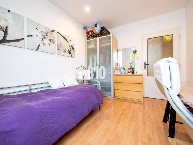 Pokoj ve 4pokojovém bytě s jednolůžkem, skříní a podlahou s dřevěným dekorem.