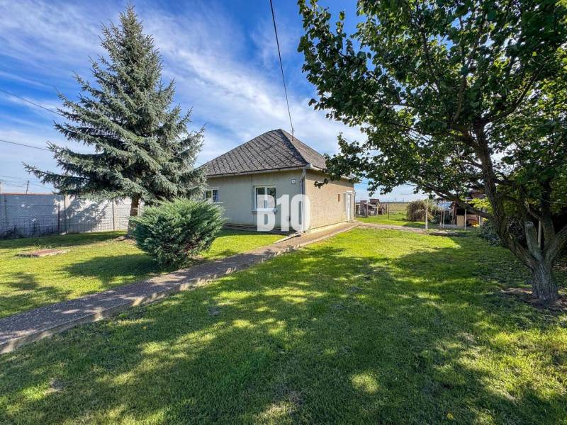 Rodinný dům v Ondrejovcích obklopený zeleným trávníkem a stromy v prostorné zahradě.