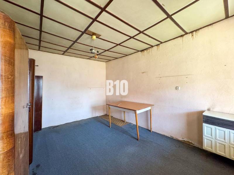 Interiér pokoje v rodinném domě, obsahující koberec, skříně a stůl.