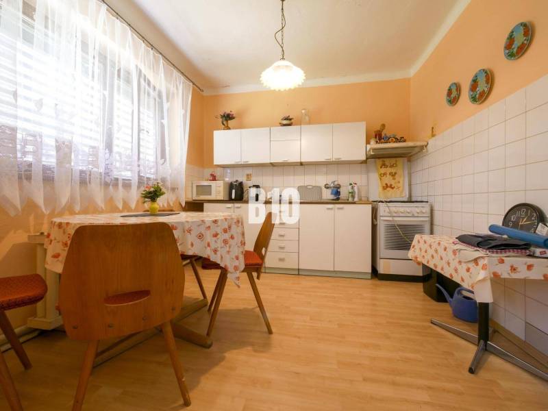 Kuchyně v rodinném domě s jídelním stolem, linkou a spotřebiči.