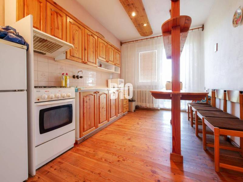 Kuchyně v rodinném domě s dřevěným dekorem a jídelním koutem.