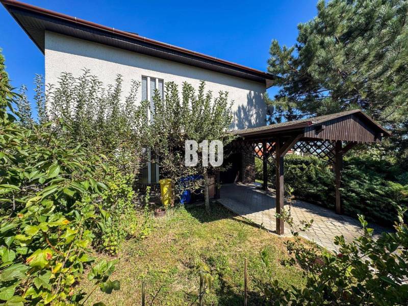 Rodinný dům na Kamennej ulici v Nitře obklopený zelení a přístřeškem pro auto.