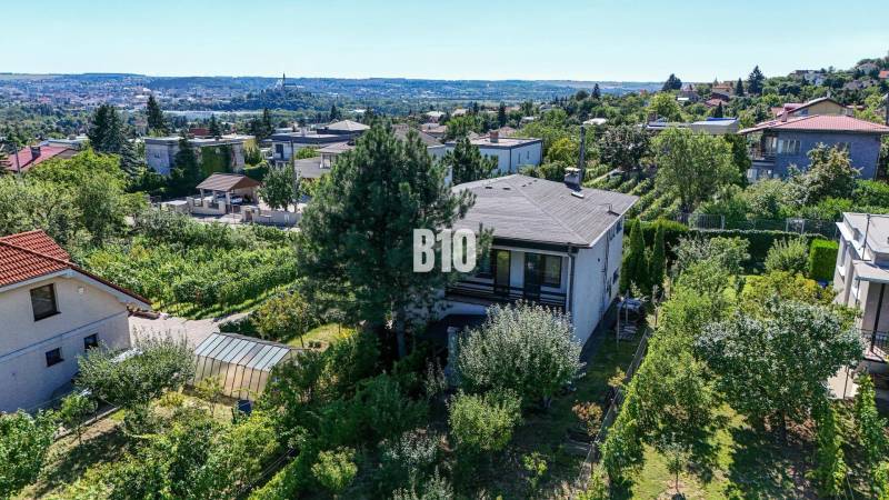 Pohled na rodinný dům na ulici Kamenná v Nitře obklopený zelení a městskou panorámou.