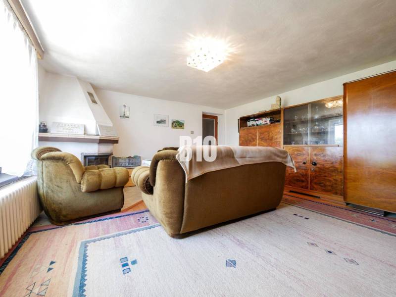 Obývací pokoj s krbem a retro nábytkem v rodinném domě, podlaha s dřevěným dekorem.