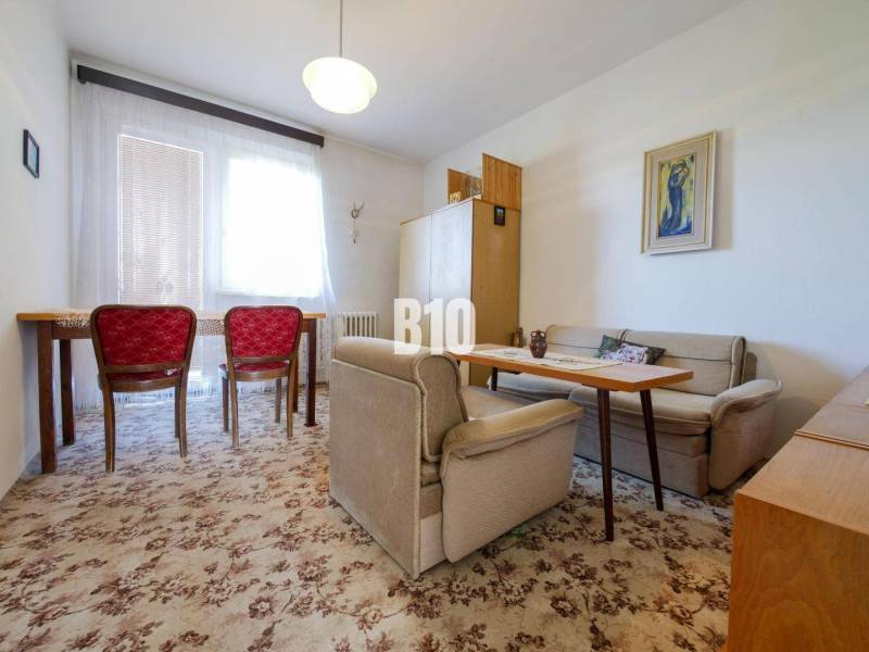 Obývací pokoj v rodinném domě s kobercem a červenými židlemi.