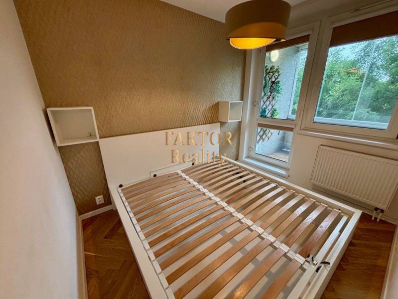 Ložnice s postelí a velkým oknem, 2pokojový byt s podlahou s dřevěným dekorem.