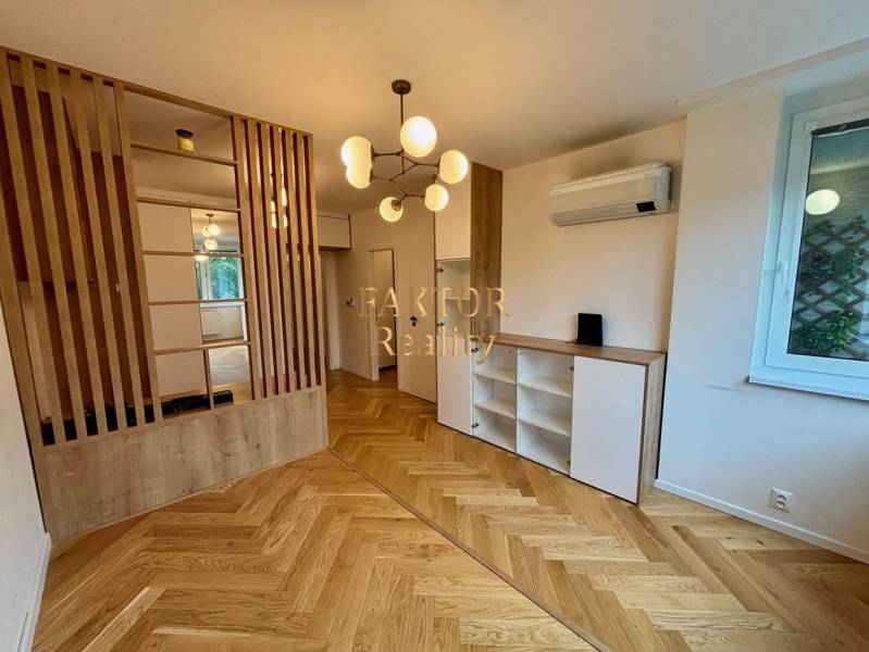 Interiér 2-pokojového bytu s podlahou s dřevěným dekorem a dělenou příčkou.