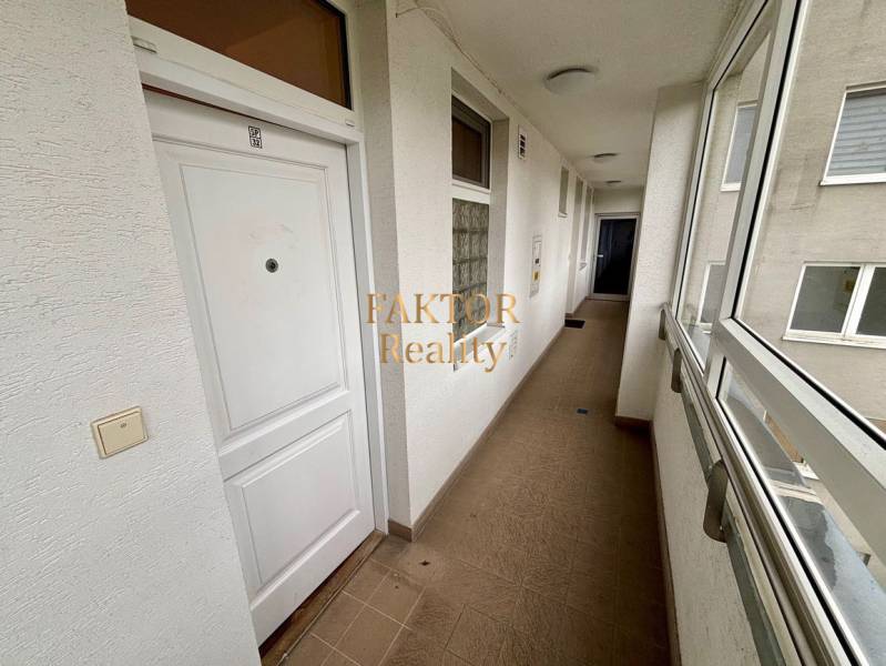 Chodba v 2-pokojovém bytě s bílými dveřmi a dlažbou.