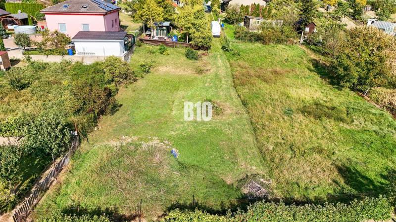 Pozemky - bydlení v Nitře s upravenou zahradou a okolními domy.