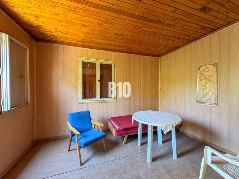 Dřevěný interiér s křeslem, stolkem a obrazem, ideální pro vinice.