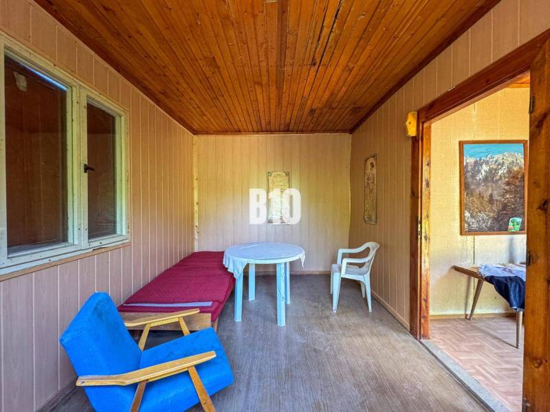 Pokoj s dřevěným stropem, křeslem, stolem a obrazy, v prostorách vinice.