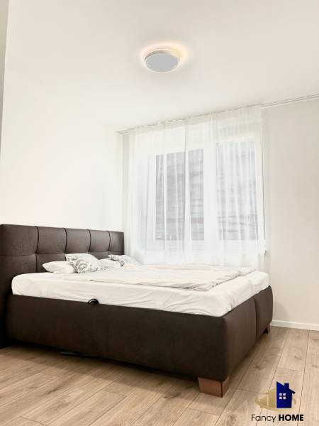 Ložnice v dvoupokojovém bytě s podlahou s dřevěným dekorem a pohodlnou postelí.