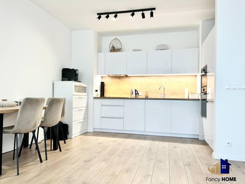 Kuchyně v 2-pokojovém bytě s podlahou s dřevěným dekorem a jídelním stolem.