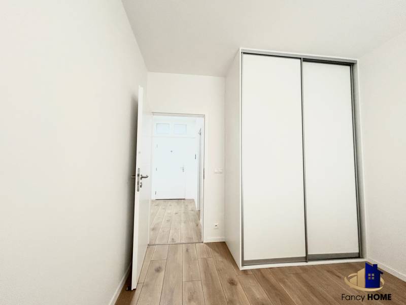 Pokoj se skříní a podlahou s dřevěným dekorem v 2pokojovém bytě.