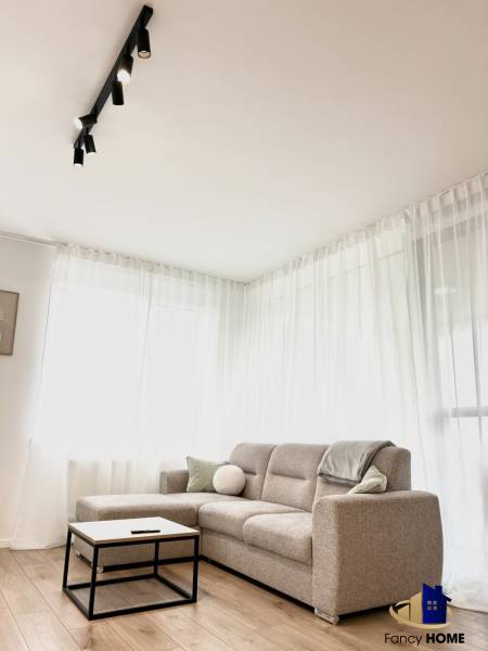 Světlý pokoj v 2-pokojovém bytě s pohovkou a podlahou s dřevěným dekorem.