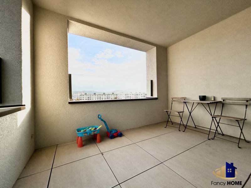 Balkon s výhledem na město, s hračkami a nábytkem v 2-pokojovém bytě.