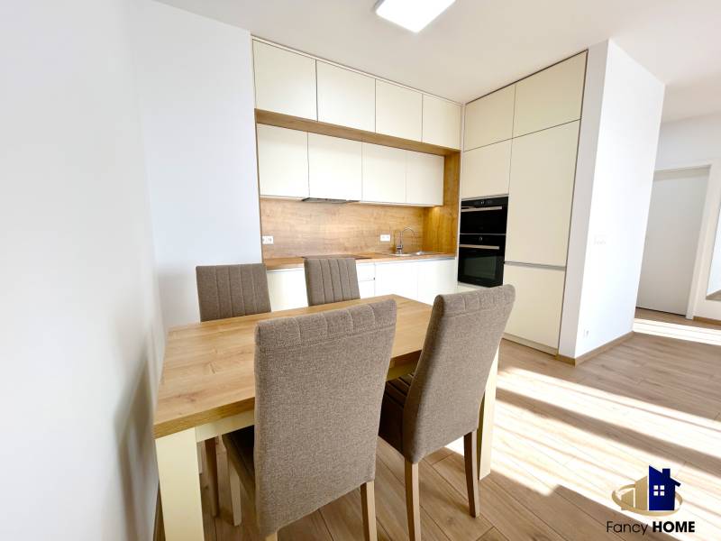 Kuchyně v 2pokojovém bytě s jídelním stolem a židlemi, podlaha s dřevěným dekorem.