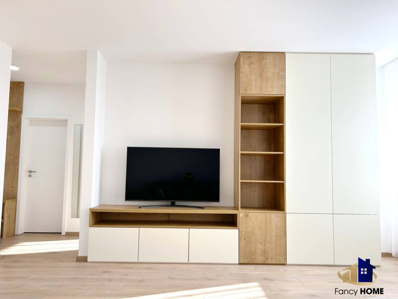 Obývací pokoj v 2-pokojovém bytě s televizorem a nábytkem s dřevěným dekorem.