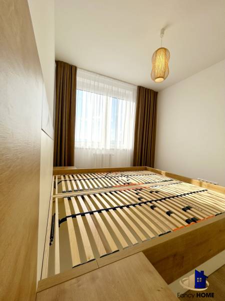 Ložnice s postelí a lampou v dvoupokojovém bytě s podlahou s dřevěným dekorem.