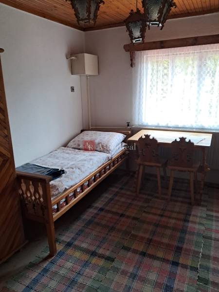 Pokoj v rodinném domě s postelí, oknem, stolem a židlemi.