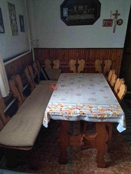 Jídelna v rodinném domě s dřevěnými židlemi a stolem, stěnu zdobí obrazy a kříž.