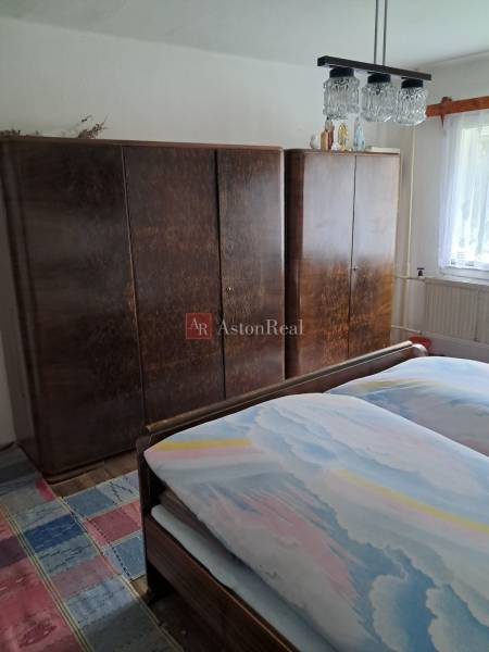 Ložnice v rodinném domě s postelí, skříněmi a kobercem s barevným vzorem.