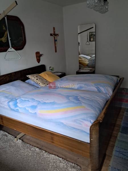 Ložnice v rodinném domě s dřevěným dekorem, velkým zrcadlem a nástěnnými dekoracemi.