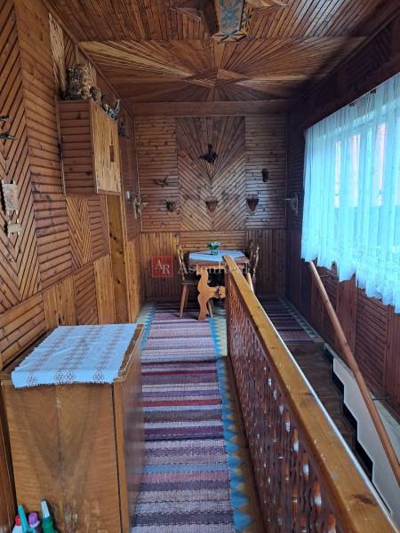 Interiér rodinného domu s podlahou s dřevěným dekorem a tradičními nástěnnými dekoracemi.