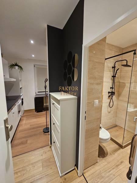 Kompaktní garsonka s podlahou s dřevěným dekorem, moderní kuchyní a designovou koupelnou.