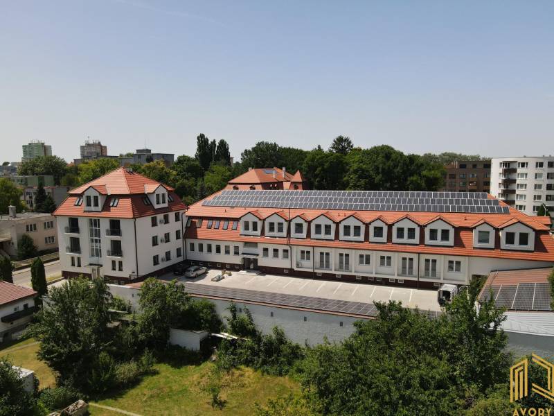 Budova na Sadové ulici v Senici s červenou střechou a solárními panely.