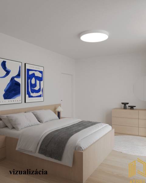 Světlá ložnice v 2-pokojovém bytě s dřevěným dekorem podlahy a obrazy na stěně.