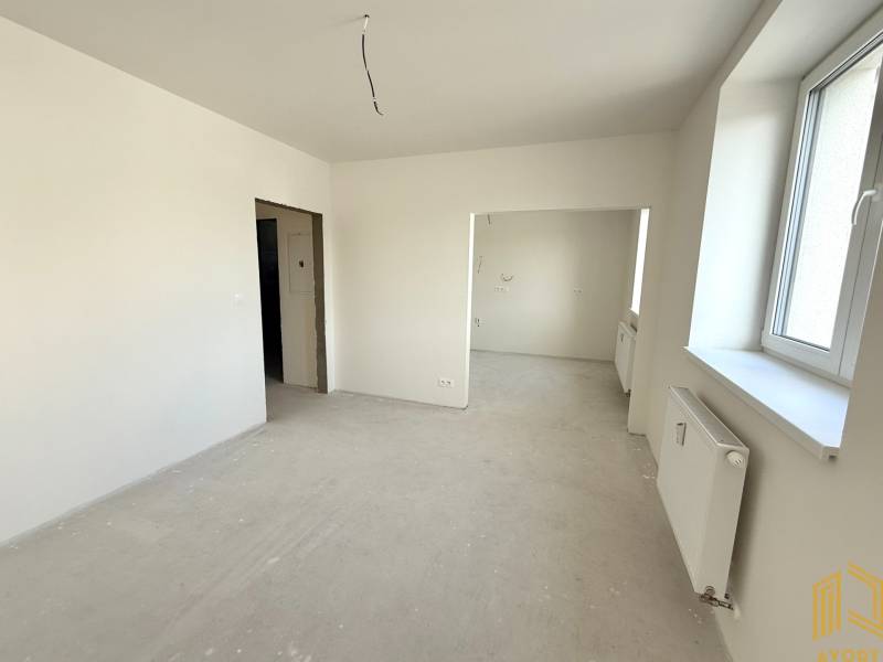 Světlý pokoj, prostorné okno, bílé stěny a radiátor v 2-pokojovém bytě.