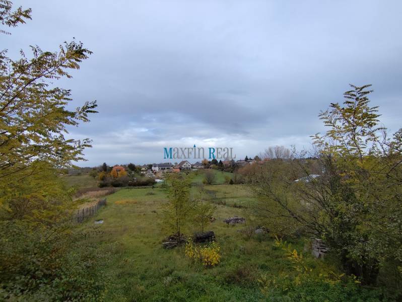 Pozemek ve městě Velký Bab, určený k bydlení, obklopený zelenými porosty a venkovskou krajinou.