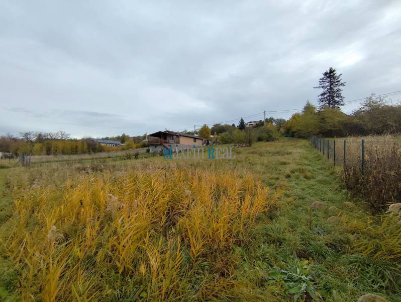 Pozemky - bydlení ve Velkém Babi s trávou a výhledem na okolní domy a stromy.