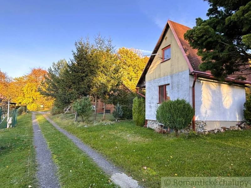 Chatka v Sološnici u cesty, obklopená stromy a trávníkem během podzimu.