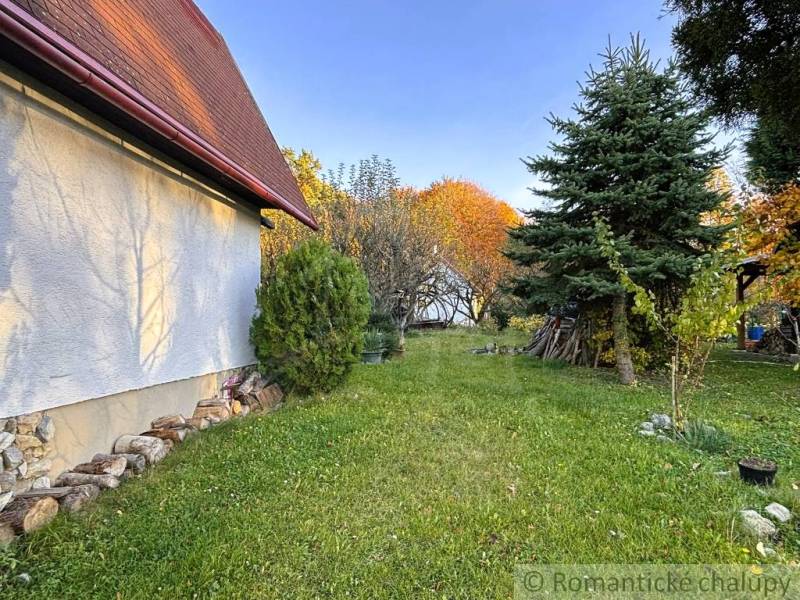 Podzim v Sološnici u chaty, obklopené zelení a jehličnany.