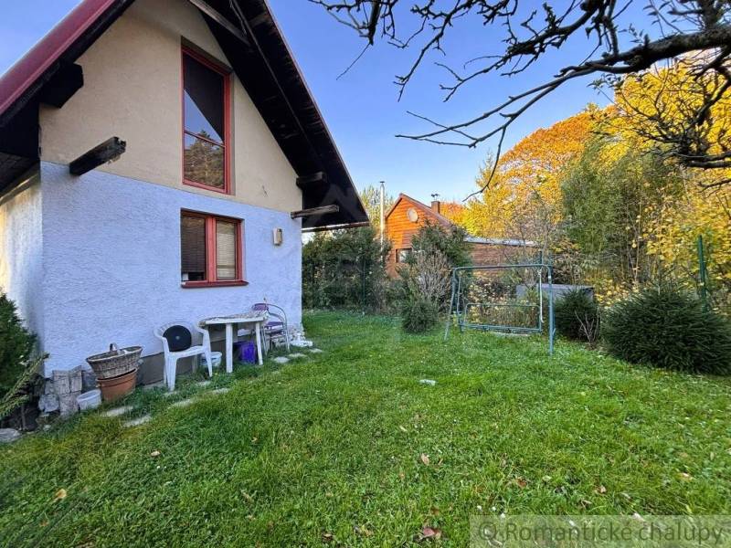 Exteriér chaty v Sološnici obklopený zeleným trávníkem a stromy.