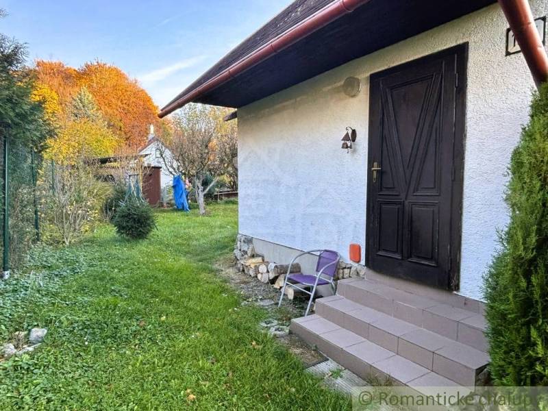 Chata v Sološnici s trávníkem a stromy v barevné podzimní krajině.