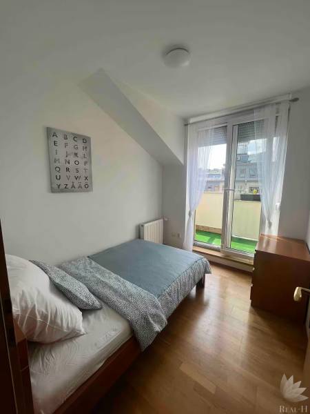 Světlý pokoj s postelí ve 3-pokojovém bytě, nástěnná dekorace s abecedou.