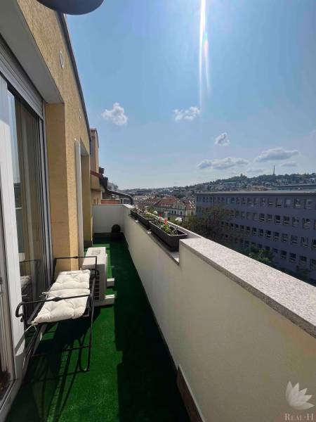 Balkon 3pokojového bytu s výhledem na panoráma města, se zelení a posezením.